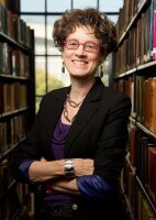 Professor Leslie Reagan, in front of stacks of books 